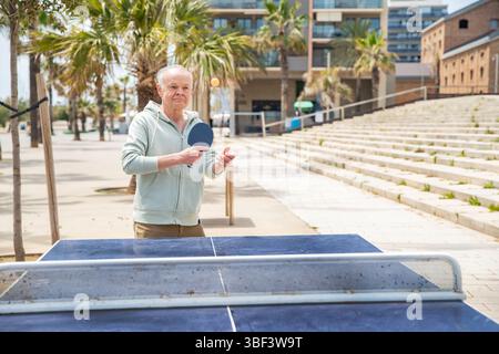 Uomo adulto che gioca a tennis da tavolo. Gioco occasionale di ping pong in movimento Foto Stock
