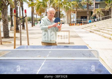 Uomo anziano che pratica il ping-pong all'aperto Foto Stock