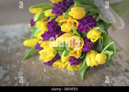 Tulipani gialli e viola giacinti bouquet di fiori su un tavolo di legno. In interni luce naturale shot con piccole profondità di campo Foto Stock