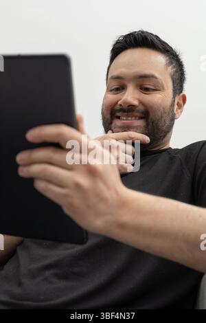 Il consulente legge gli ultimi aggiornamenti del settore sul suo tablet mentre è seduto in uno spazio di coworking. Foto Stock
