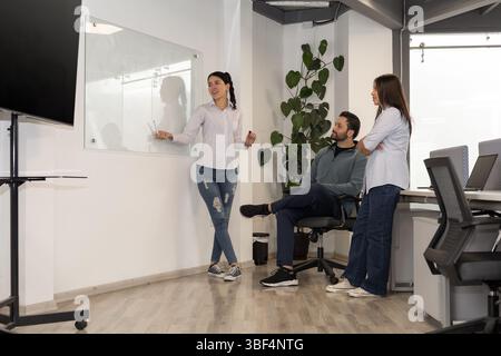Tre professionisti si riuniscono intorno a un tavolo, concentrati e impegnati, collaborando per elaborare la migliore strategia di vendita per il successo. Foto Stock