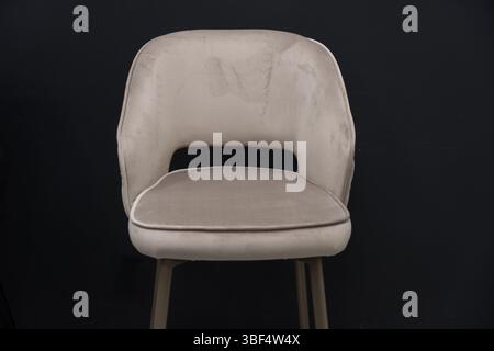 Uno studio fotografico ravvicinato presenta un'elegante sedia da pranzo in velluto taupe con un esclusivo schienale sagomato e eleganti gambe in metallo dorato, ideale per il moderno Foto Stock