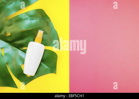 Una giungla tropicale palm foglie di monstera e protezione solare bottiglia vuota mockup sul luminoso giallo e rosa bicromia sfondo della carta. Vacanze estive creative f Foto Stock