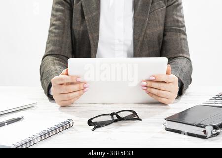 Primo piano donna che tiene le mani sul tablet. Donna d'affari che lavora alla scrivania. Donna aziendale in tuta sul posto di lavoro in ufficio. Manager che utilizza il digitale Foto Stock