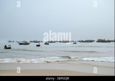 Navi da pesca vietnamite e tradizionali barche a cesto tondo con pescatori in mare in un villaggio di pescatori in Vietnam Foto Stock