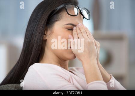 donna che si sfrega il naso sotto gli occhiali Foto Stock