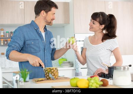 giovane coppia che gioca in cucina mentre cucina Foto Stock