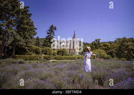 Una donna sta in piedi in un campo di fiori viola Foto Stock