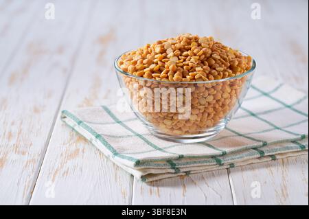 Far asciugare i piselli gialli in un recipiente di vetro trasparente su un tavolo leggero, con messa a fuoco selettiva. Foto Stock