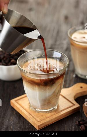Versare l'espresso sul bicchiere con latte fresco freddo, lavorare per es Kopi Susu o Dirty latte Foto Stock
