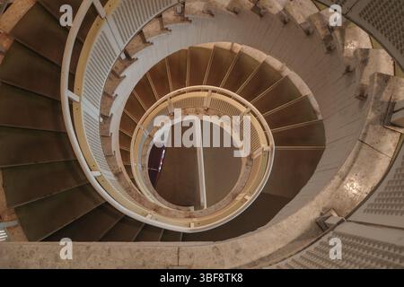 Una fotografia ad alto angolo cattura gli ipnotici motivi astratti di una scala a spirale che scende. Foto Stock