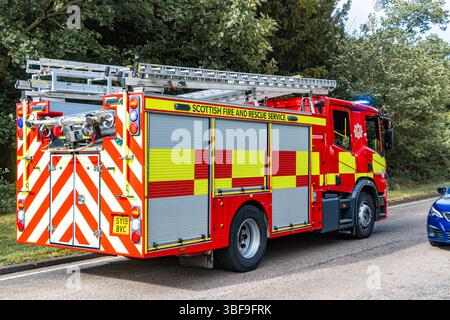 Un motore antincendio scozzese Fire and Rescue Service su un grido su una strada alberata, dotato di scale e attrezzature per la risposta alle emergenze Foto Stock