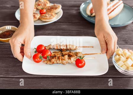 Spiedini di pollo con yakitori grigliati su un piatto bianco serviti come spuntino al rustico tavolo da bar, spuntino di birra, pasti informali Foto Stock
