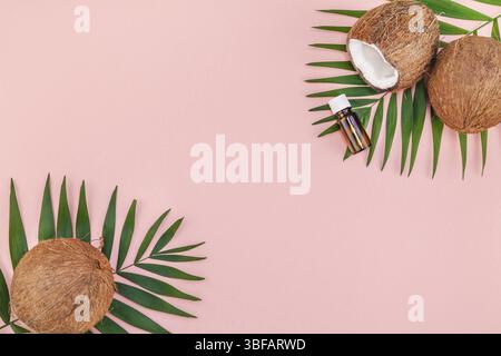 Piatti creativi laici vista superiore del verde tropicale di foglie di palma di cocco e frutta di olio di noce di cocco cosmetici per la pelle e cura dei capelli su carta rosa copia in background Foto Stock