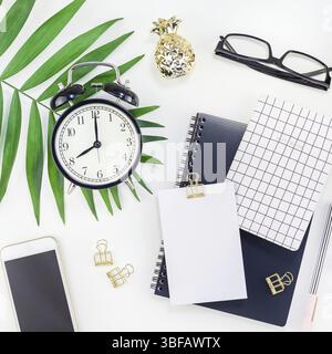 Vista superiore piana ufficio laici workspace desk design in stile forniture per ufficio sveglia tropical palm lascia la fotocamera dello smartphone spazio copia in bianco nero backgr Foto Stock