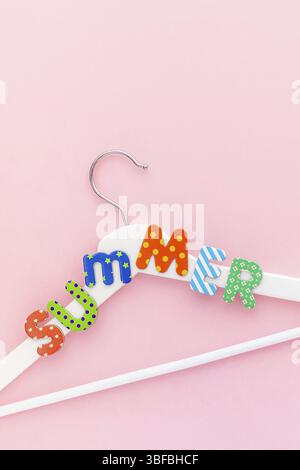 Creative vista superiore piatto bianco laici i portabiti in legno estate testo rosa pastello sfondo spazio copia stile minimalista. Il modello femminile di moda blog sociale Foto Stock