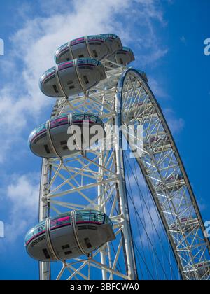 Guardando verso l'occhio di Londra, una famosa grande ruota panoramica nella città inglese di Londra. Vista dal basso delle cabine della ruota panoramica con sfondo blu Foto Stock