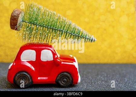 Auto giocattolo rossa porta un albero di Natale per la vacanza Foto Stock