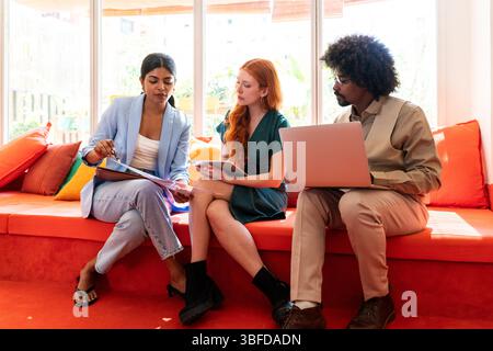 Piccolo gruppo multietnico di imprenditori che si incontrano in un ufficio aziendale di coworking - giovani colleghi che lavorano insieme in un creativo Foto Stock