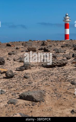 Fuerteventura: Rocce nere e vista sul Faro de Toston (faro di Toston o El Cotillo), faro attivo a Punta de la Ballena (punto balena) Foto Stock