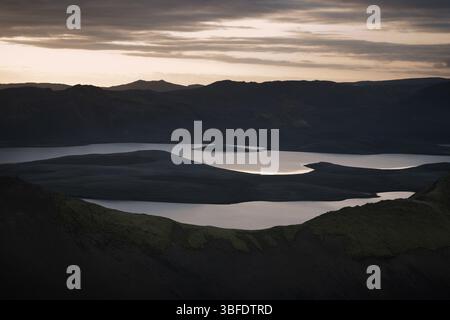 Paesaggio aperto islandese con montagne maestose, laghi tranquilli e uno splendido tramonto che dipinge il cielo in tonalità calde: Un momento perfetto di tranqu naturale Foto Stock