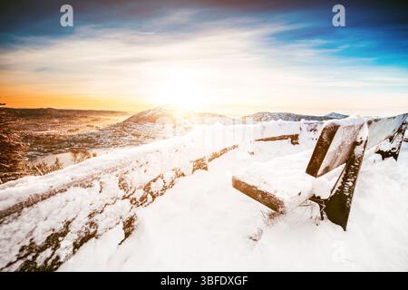 splendido paesaggio invernale con panchina in legno dalla cima di una montagna Foto Stock