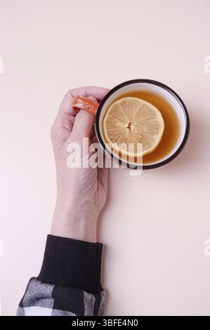 Tazza da presa femminile con tè e limone su sfondo beige, copia spazio Foto Stock