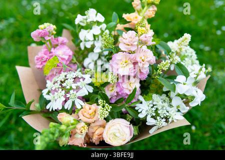 Bouquet di fiori avvolti di fiori primaverili misti. Splendida disposizione di fiori freschi color pastello. Bouquet di compleanno con draghi d'ape e matthio Foto Stock