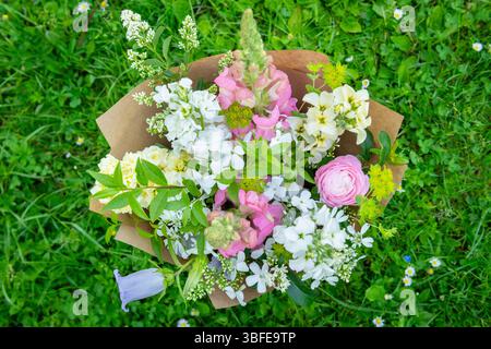 Bouquet di fiori avvolti di fiori primaverili misti. Splendida disposizione di fiori freschi color pastello. Bouquet di compleanno con draghi d'ape e matthio Foto Stock