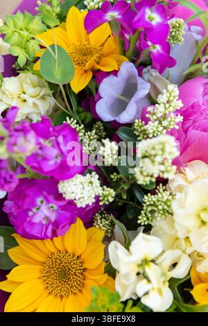 Bouquet di fiori avvolti di fiori primaverili misti. Splendidi fiori freschi dai colori vivaci. Bouquet di compleanno con peonie e girasoli Foto Stock