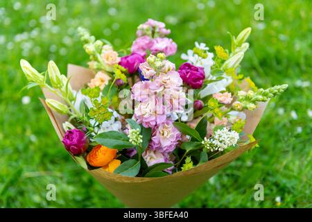 Bouquet di fiori avvolti di fiori primaverili misti. Splendidi fiori freschi dai colori vivaci. Bouquet di compleanno con draghi dentici, peonie A. Foto Stock