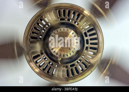 Vista ravvicinata di un ventilatore a soffitto in ottone rotante in movimento Foto Stock