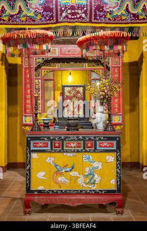 HOI AN, VIETNAM, APR 26 2025, tradizionale altare asiatico con decorazioni ornamentali in un tempio la sera Foto Stock