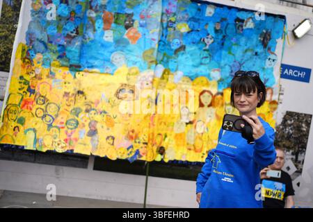 Una donna fa un selfie con un'opera d'arte che usa i volti dei bambini mentre le persone prendono parte alla marcia della campagna di solidarietà Ucraina nel centro di Londra, chiedendo alla Russia di restituire i bambini ucraini. Data foto: Domenica 1 giugno 2025. Foto Stock