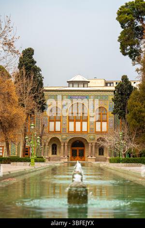Teheran, Iran - 12 novembre 2023: Piscina di riflessione e alberi che portano alla facciata del Palazzo Golestan Foto Stock