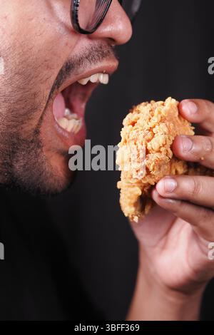 L'uomo ama il pollo fritto croccante durante un pasto Foto Stock