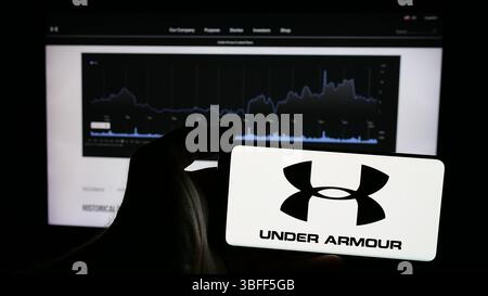 Stoccarda, Germania - 01-15-2025: Persona che possiede un telefono cellulare con il logo della società americana di abbigliamento sportivo Under Armour Inc. Sullo schermo davanti alla pagina web Foto Stock