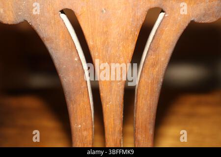 Primo piano dello schienale di una sedia in legno, con particolare attenzione alle spranghe verticali dello schienale. Il design comprende tre elementi verticali con bordi interni curvi. Foto Stock