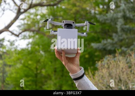 Uomo e tecnologia: Drone con carico in mano a una donna primo piano sullo sfondo della natura Foto Stock