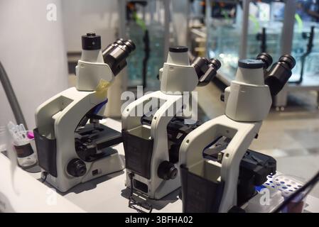 Tre microscopi moderni in un luminoso ambiente di laboratorio a Singapore, che mostrano ricerca scientifica e precisione tecnologica. Foto Stock
