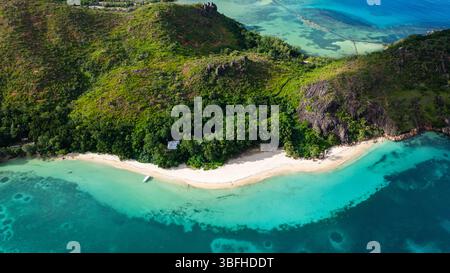 Una spiaggia tropicale nascosta circondata da dense colline verdi e acque turchesi. Curieuse, Seychelles. Foto Stock