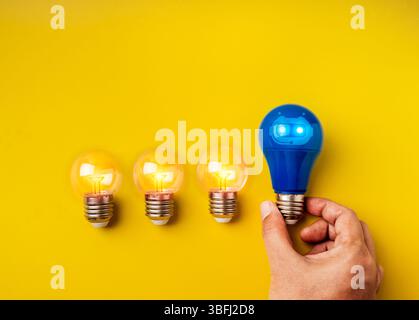 Strumenti di INTELLIGENZA ARTIFICIALE, tecnologia e idee di innovazione, individualità, leadership, concetti creativi. Icona chat bot sulla lampadina blu in mano, vicino a un piccolo labbro trasparente Foto Stock