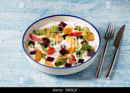 Insalata di yogurt colorata con arance grigliate, barbabietole, pomodori ciliegini e verdure Foto Stock