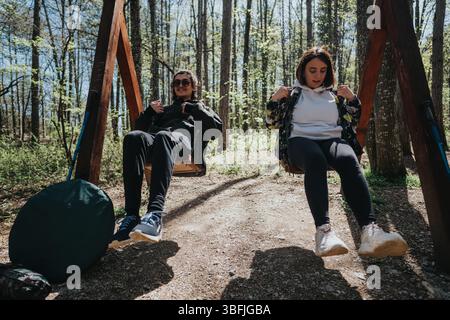 Coppia che si gode un momento rilassante sulle altalene in una foresta serena Foto Stock