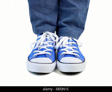 Foto corta di un giovane in piedi isolato in bianco con scarpe di tela Foto Stock