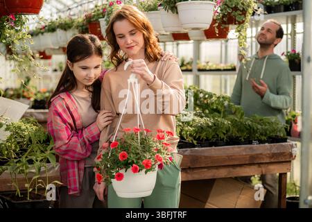 Famiglia che ama il giardinaggio insieme in una serra Foto Stock