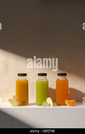 Tre bottiglie di succo vivace insieme a pezzi di frutta Foto Stock