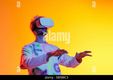 Un giovane esplora un mondo virtuale vivido, affascinato dai suoi occhiali VR. Foto Stock