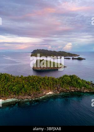 Vista aerea della lussureggiante isola e della barriera corallina di Raja Ampat al tramonto Foto Stock