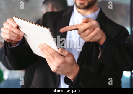Primo piano di uomini d'affari che usano il tablet e puntano durante una riunione professionale Foto Stock